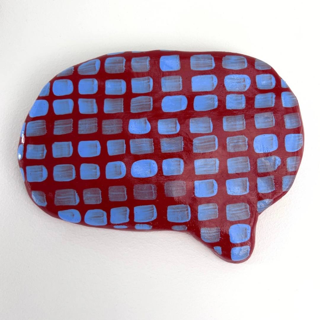 Ceramic speech bubble, deep red with a grid of pale blue squares
